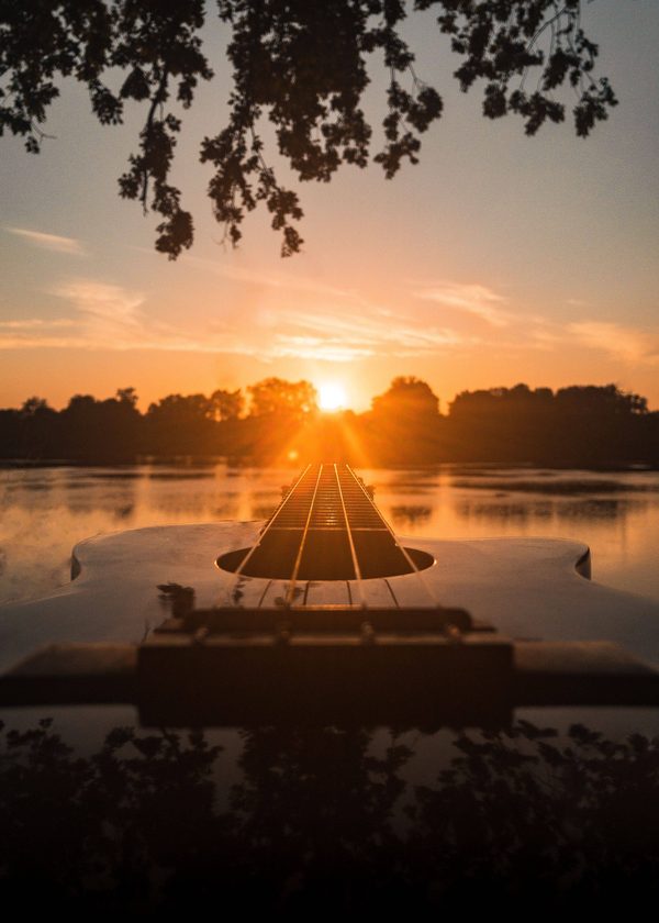 Guitare au coucher du soleil au bord d'un lac